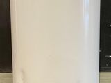 une photo d'un chauffe-eau blanc posé sur un sol carrelé
