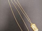 a close up of a gold necklace with a bird on it