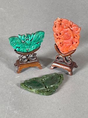 trois pièces de jade et de corail sculpté, présentées sur un socle