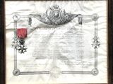 un vieux document orné d'un ruban rouge et d'une médaille