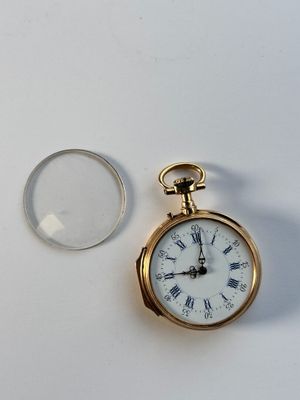 une montre de poche en or avec des chiffres romains et une loupe