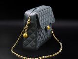 a black quilted bag with a gold chain on a black background