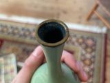 a person holding a green vase on a rug