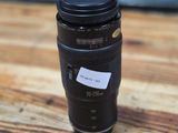 the lens is sitting on a wooden table next to a cup