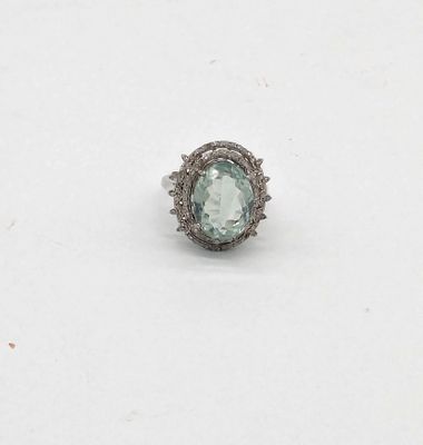 une bague ovale sertie d'une aigue-marine et de diamants, posée sur un fond blanc