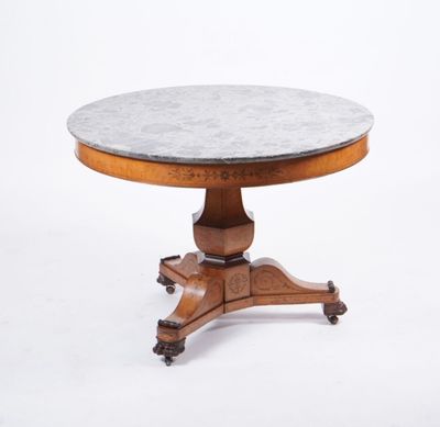 une table à plateau rond en marbre, montée sur roulettes et dotée d'un piètement en bois