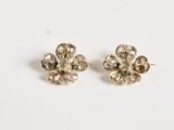 a pair of silver flower earrings on a white surface