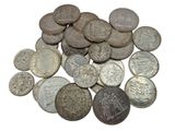 a pile of old silver coins on a white surface
