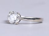 a close up of a single stone diamond ring on a white surface