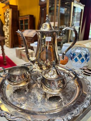 a silver tea set on a silver tray on a table