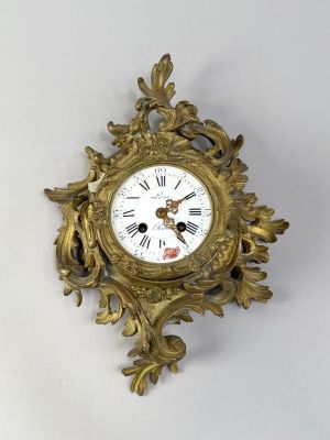 a gold clock on a white wall with a white background