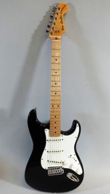 an electric guitar sitting on top of a white table next to a black guitar