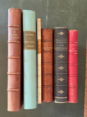 several old books are lined up on a shelf in a library