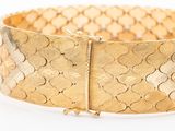 a close up of a gold bracelet on a white surface