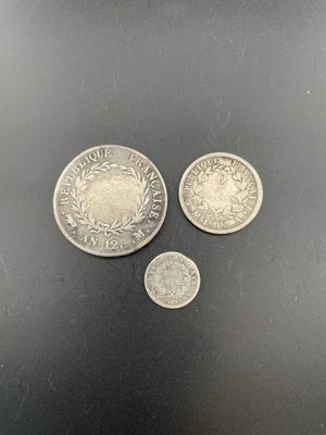 three silver coins sitting next to each other on a black surface