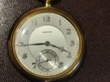 a close up of a pocket watch on a leather surface