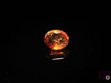 a close up of an orange diamond on a black surface