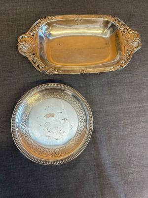 une assiette en argent et un plateau en argent posés l'un à côté de l'autre sur une table