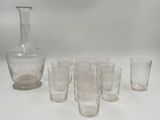 plusieurs verres et une carafe posés sur une table devant un fond blanc