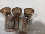 quatre tasses en argent posées sur une nappe blanche