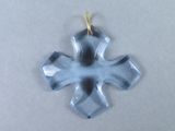 une photo d'un pendentif en forme de croix en verre posé sur une surface blanche