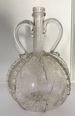 a clear glass bottle with a handle on a table
