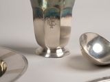 a silver cup sitting on a table next to other silver dishes