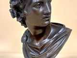 bronze bust of a woman with curly hair on a pedestal