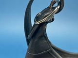 a black purse with a metal handle on a blue background