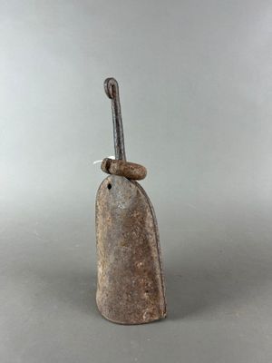 une vieille cloche munie d'une poignée métallique, posée sur une surface grise