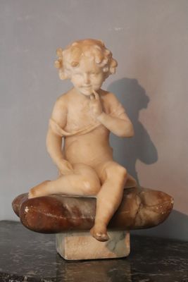 a small statue of a child sitting on a rock