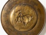 a metal plate with a picture of a man riding a bull