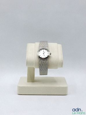 une montre posée sur un socle, sur une surface blanche