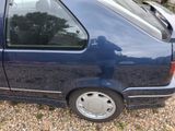 a small blue car parked in a gravel lot