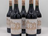 six bouteilles de vin sont alignées sur une surface blanche
