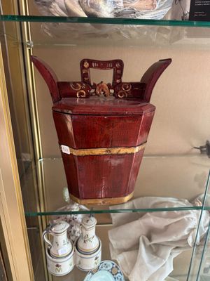 a glass display case with a wooden bucket on it