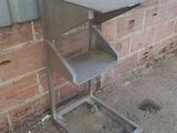 une table en métal surmontée d'une étagère, placée devant un mur de briques