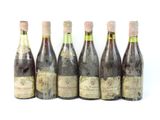 six bouteilles de vin posées les unes à côté des autres sur une surface blanche