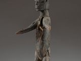 une statue en bois représentant un homme tenant un couteau dans la main droite