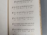 an open book with music notes on it sitting on a table