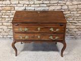 une petite commode en bois posée sur un socle