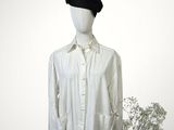 shirt on a mannequin stand with a vase of flowers in front of it