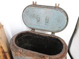 an old metal trash can sitting next to a piece of wood