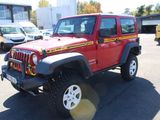 a red jeep parked in a parking lot with other cars in the background