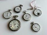 many different types of pocket watches displayed on a table