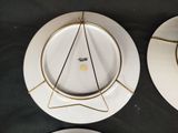 two white plates with gold rims on a black table