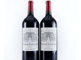 two bottles of red wine sitting next to each other on a white surface