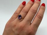 an image of a woman ' s hand holding a ring with a purple stone
