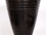 un vase noir posé sur une surface blanche