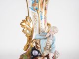 a figurine of a man sitting on top of a vase